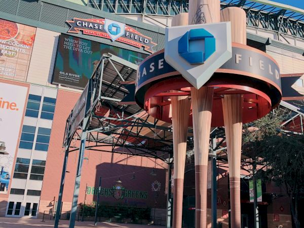 The image shows the entrance to Chase Field with large baseball bats as pillars and a sign above the entrance.
