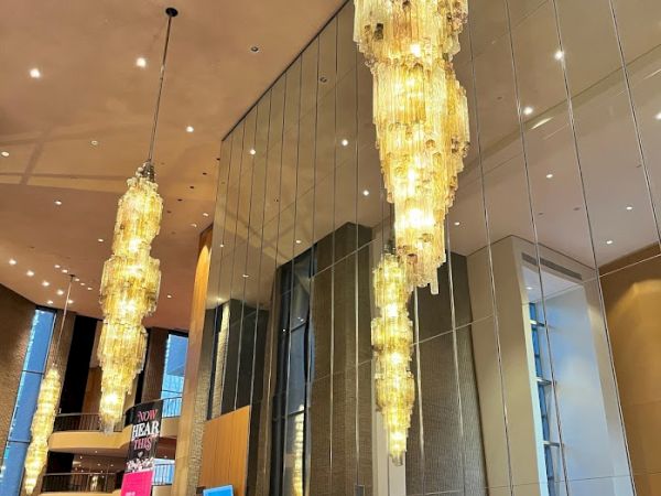 A hotel lobby with large chandeliers, mirrored walls, and people at a reception desk.