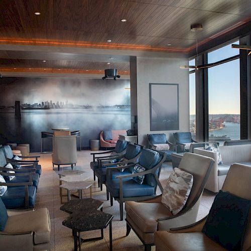 A modern lounge featuring comfortable seating, large windows with a scenic view, and contemporary decor, creating a relaxing atmosphere.